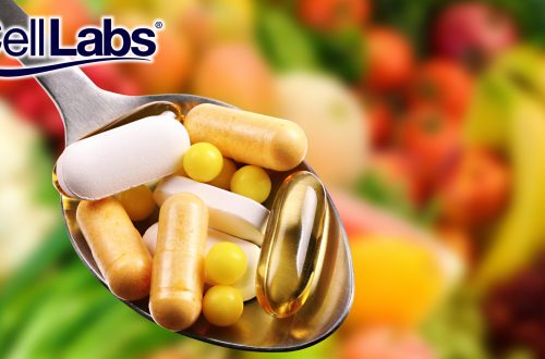 Image of spoon with different health supplement capsules with a background of fruits and vegetables.