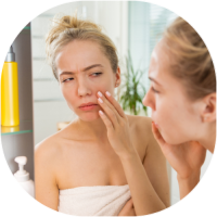 Image of woman looking at her dry skin in the mirror.
